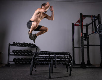 Man performing a box-jump on stacked JumpSport trampolines during a trampoline HIIT workout.