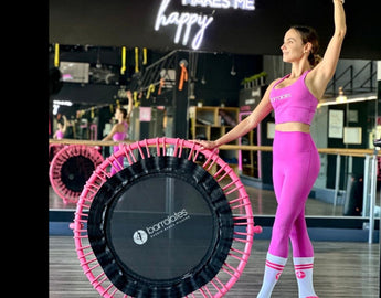 Barrelates founder in a ballet pose next to a JumpSport trampoline for a Barre Trampoline Exercise blog.