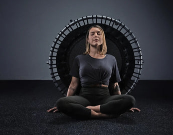 Woman peacefully leaning with her back against a JumpSport Fitness trampoline.