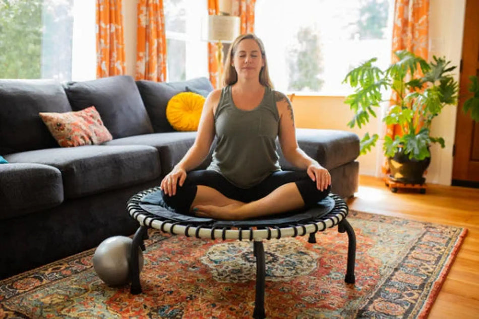 Woman sitting on a JumpSport wellness trampoline, representing calm and relaxation.