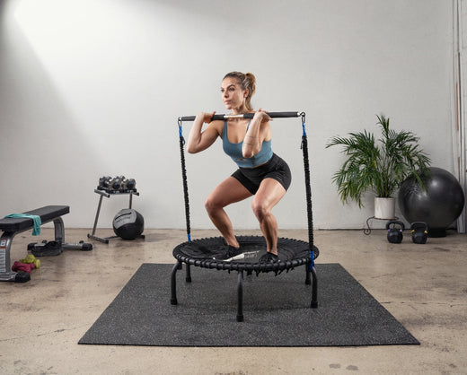 Woman squatting on a JumpSport trampoline during a strength training workout.