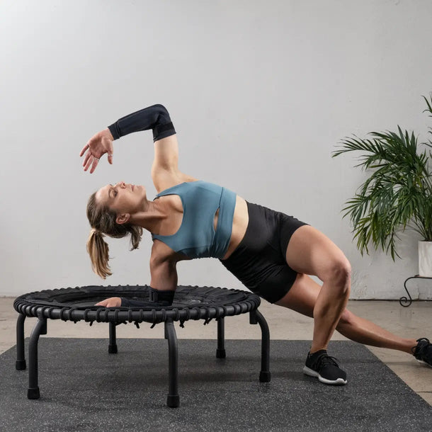 Girl doing side-stretch pose on the padded petal mat version of the JumpSport 39 inch PREMIUM trampoline