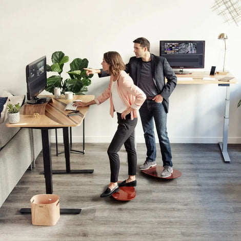 Woman and Man working at standing desks standing on alleyoop ergo rocker boards by Wurf