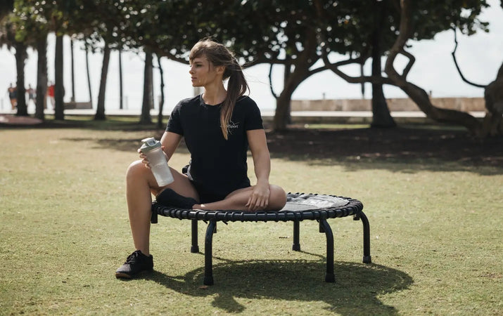 Woman resting on her trampoline at the park for fitness on-the-go