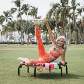 Woman stretching on fitness trampoline with powHER bands